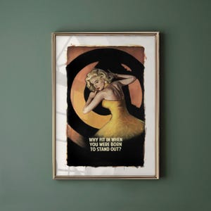 Puede incluir: Impresión enmarcada de estilo vintage que presenta a una mujer con un vestido amarillo sobre un fondo negro y naranja. La impresión incluye el texto: "WHY FIT IN WHEN YOU WERE BORN TO STAND OUT?" La obra de arte está en un marco dorado.