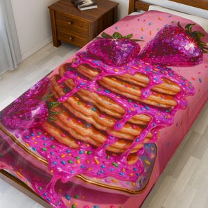 May include: A pink bedspread featuring a stack of pancakes with pink syrup and colorful sprinkles. Two large, sparkling, pink strawberries are on top. The bedspread is on a wooden bed frame.