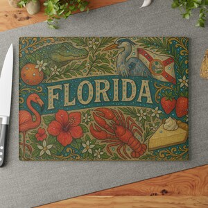 May include: Rectangular cutting board with a Florida theme. The design features an alligator, a heron, a flamingo, a lobster, strawberries, and a slice of pie. The word "FLORIDA" is written in large letters across the center.