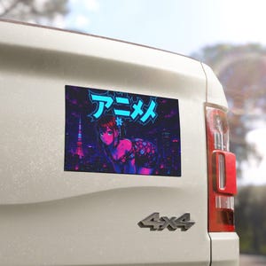 May include: A rectangular sticker featuring an anime-style illustration of a character with dark hair and a floral top, set against a dark city skyline with a glowing tower. The Japanese text "アニメ" is displayed in bright cyan above the character.