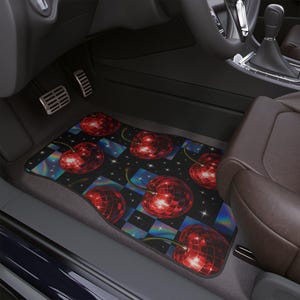 Könnte beinhalten: Schwarze Auto-Fußmatte mit einem Muster aus roten Diskokugel-Kirschen. Das Design umfasst einen karierten Hintergrund mit schillernden Quadraten und kleinen weißen Sternen. Die Matte befindet sich in einem Autoinnenraum.