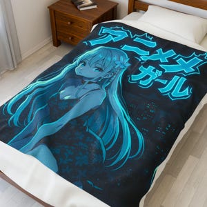 Könnte beinhalten: Eine schwarze Decke mit einer blau-blauen Anime-Illustration eines Mädchens mit langen blauen Haaren und einem Blumenkleid. Die Decke hat japanischen Text in leuchtender blauer Farbe. Der Hintergrund zeigt eine Stadtlandschaft.