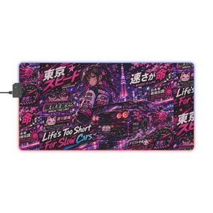 May include: A rectangular mousepad with a vibrant design featuring a purple sports car, anime-style artwork, and Japanese text. The mousepad has a black border and a USB connector.