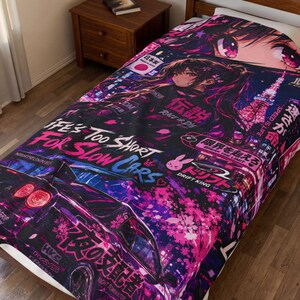 Könnte beinhalten: Eine Decke mit einem lebendigen Anime-Design, das ein Auto, eine Stadtlandschaft und japanischen Text zeigt. Die Farbpalette umfasst Pink, Lila und Schwarz. Der Text enthält "Life's Too Short For Slow Cars" und "Drift King".