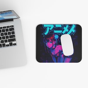 May include: A black mouse mat featuring a vibrant anime-style illustration. The design includes a young woman with blue eyes and a flower in her hair, with Japanese text. A white computer mouse is on the right.