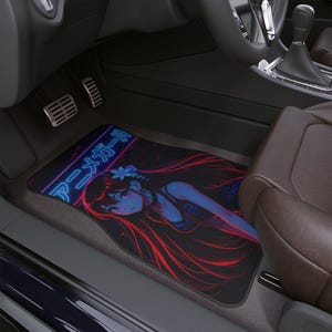 Könnte beinhalten: Schwarze Auto-Fußmatte mit einer Anime-Illustration eines Mädchens mit langen roten Haaren und blauen Akzenten. Die Matte trägt den japanischen Text "Anime Girl" im Neon-Stil. Die Matte befindet sich im Fußraum des Fahrers.
