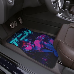 Op de afbeelding: Vloermat voor auto's met een levendige anime-stijl illustratie in blauw, roze en paars. Het ontwerp bevat Japanse tekst en een gestileerde vrouwelijke figuur. De mat ligt in een auto.