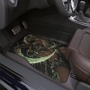 May include: Black car floor mat featuring a detailed anime-style illustration of a woman with long white hair, accented with green glowing elements. The mat is rectangular and fits the car's footwell.