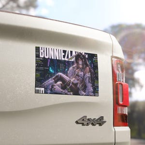 May include: A rectangular sticker featuring a magazine cover titled BUNNIEZLAND with a dark, futuristic aesthetic. The artwork displays a character with long dark hair, wearing white and black tech-inspired clothing, set against a neon-lit background.