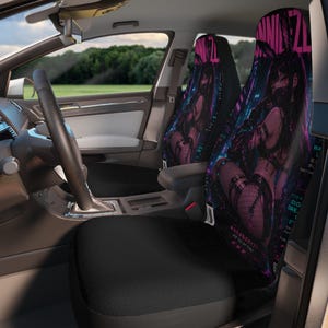 May include: A pair of car seat covers featuring a vibrant anime-style graphic of a character with long dark hair and bunny ears. The design incorporates neon pink and blue accents, Japanese text, and the English phrase ARE YOU MY TYPE?