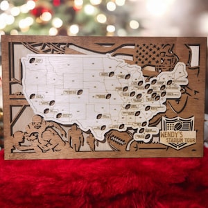 May include: A wooden map of the United States with a football design. The map shows the locations of different NFL stadiums. The map is decorated with a football player and the text "WENDY'S STADIUM TOUR".