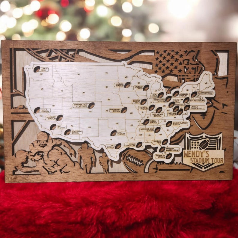 May include: A wooden map of the United States with a football design. The map shows the locations of different NFL stadiums. The map is decorated with a football player and the text "WENDY'S STADIUM TOUR".