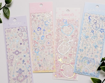 Peut inclure: Quatre feuilles d'autocollants holographiques irisés dans des tons rose, bleu et violet. Les autocollants présentent des cœurs, des étoiles, des clés, des chaînes et d'autres motifs mignons. Les autocollants sont emballés sur des feuilles transparentes avec une bordure blanche et le mot "GALICICI" imprimé sur chaque feuille.