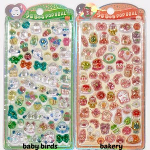 Puede incluir: Dos hojas de pegatinas con pegatinas transparentes y brillantes. Una hoja presenta dise&ntilde;os de p&aacute;jaros beb&eacute;s, la otra pegatinas con tem&aacute;tica de panader&iacute;a. Las pegatinas son de varios colores, incluyendo azul, verde, rosa y amarillo. El embalaje incluye texto japon&eacute;s.