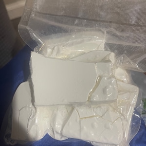 以下が含まれることがあります： 白い粉末状の物質が透明なビニール袋に入っています。粉末はいくつかの破片に砕かれ、ビニールを通して見えています。