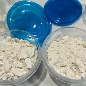 Puede incluir: Dos recipientes de plástico transparente con polvo blanco en su interior. Los recipientes tienen tapas azules.