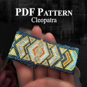 Może przedstawiać: Wzór PDF na bransoletkę z koralików o geometrycznym wzorze w odcieniach niebieskiego, złotego i białego. Wzór nazywa się "Kleopatra".