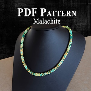 Pode incluir: Um colar de contas verde e dourado em um suporte preto. O colar é feito com pequenas contas de sementes e tem um padrão geométrico. O texto "PDF PATTERN Malachite" é exibido acima do colar.