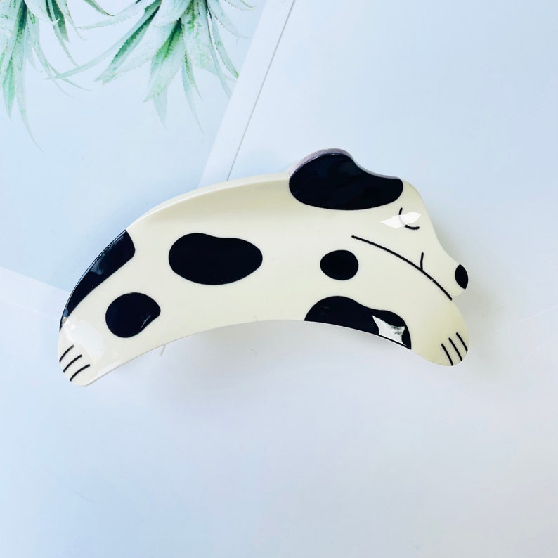 May include: A white and black ceramic hair clip shaped like a sleeping dalmatian dog.