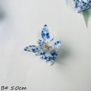 K&ouml;nnte beinhalten: Blau-wei&szlig;er Schmetterlings-Haarklammer mit Federspanner. Die Klammer ist 5,0 cm gro&szlig;.
