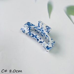 K&ouml;nnte beinhalten: Eine wei&szlig;e und blaue Haarklammer mit Muster. Die Klammer ist 8 cm lang.