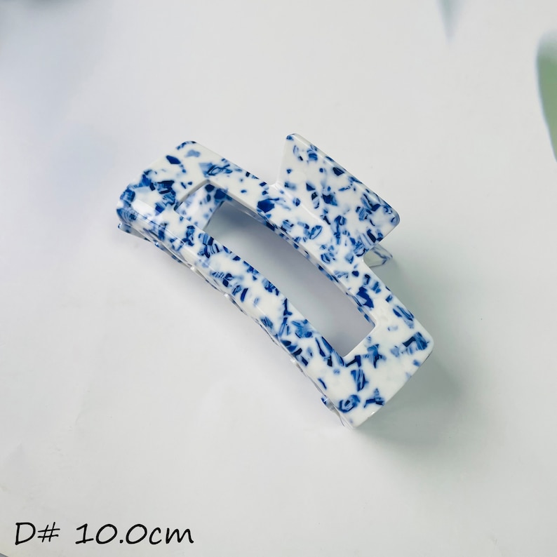 K&ouml;nnte beinhalten: Haarspange in Form einer Kralle mit wei&szlig;em und blauem Muster, etwa 10 Zentimeter lang.