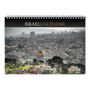 Może przedstawiać: Kalendarz ścienny ze spiralą, zatytułowany ISRAEL CALENDAR białymi i złotymi literami na czarnym pasku. Okładka przedstawia panoramiczne zdjęcie Jerozolimy, eksponujące złotą Kopułę na Skale oraz logo marki Saboke w prawym rogu.