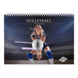 Peut inclure: Un calendrier mural à spirale intitulé VOLLEYBALL CALENDAR présentant une photographie d'un joueur en uniforme bleu foncé avec des genouillères bleues effectuant une manchette avec un ballon de volley blanc dans une grande salle.