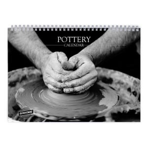 Może przedstawiać: Czarno-biały kalendarz ścienny z napisem POTTERY CALENDAR i spiralą u góry. Okładka przedstawia kontrastowe zdjęcie dłoni formujących glinę na kole garncarskim, z nazwą marki SABOKE wydrukowaną w lewym dolnym rogu zdjęcia.