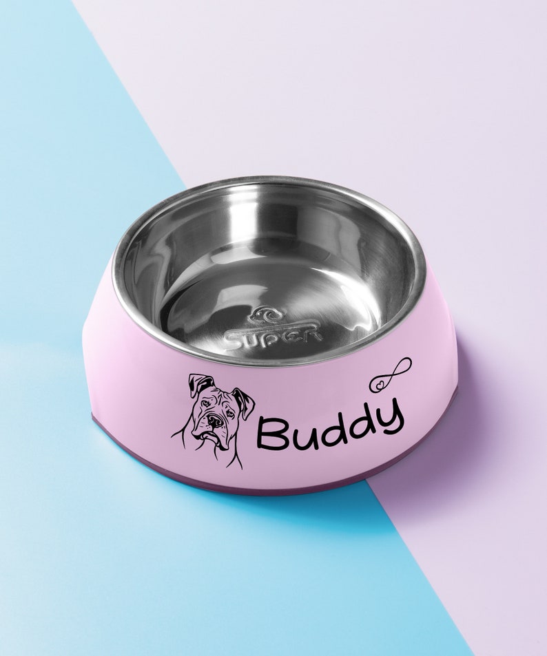 May include: Pink stainless steel pet bowl with a black silhouette of a dog and the name "Buddy" printed on the side.