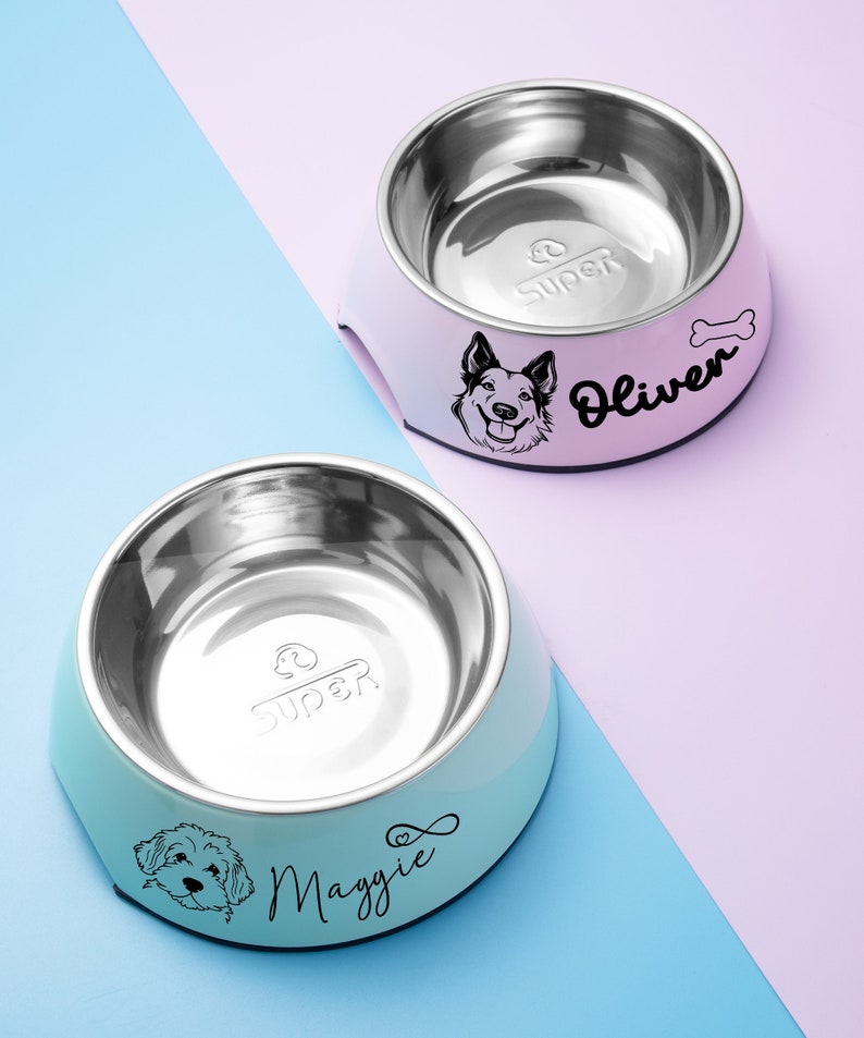 May include: Two stainless steel dog bowls, one blue and one pink. The blue bowl has a white dog silhouette and the text "Maggie" with a heart symbol. The pink bowl has a black dog silhouette and the text "Oliver" with a bone symbol. Both bowls have the word "Super" printed on the inside.