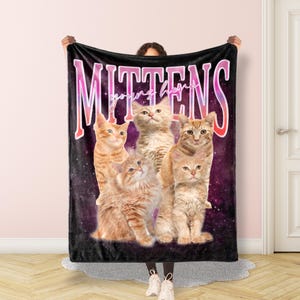 May include: A black fleece blanket with a galaxy print and the text "Mittens young heroes" in pink and white. Five orange tabby kittens are arranged in a row on the blanket.
