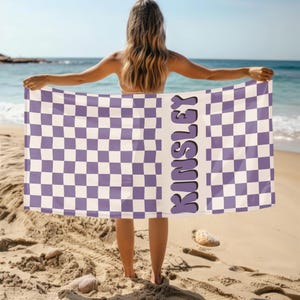 May include: A purple and white checkered beach towel with the name "Kinsley" printed in a purple retro font.