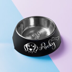 May include: Black and silver dog bowl with a white silhouette of a dog and the name "Rocky" on the side.