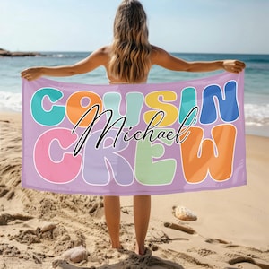 May include: A purple beach towel with the text "Cousin Crew" in colorful, oversized letters. The name "Michael" is written in black cursive script below the text.