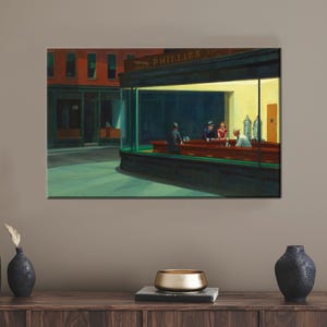 Może przedstawiać: Wydruk na płótnie obrazu Edwarda Hoppera "Nighthawks". Dzieło przedstawia bar z trzema klientami i kelnerem przy ladzie. Bar jest jasno oświetlony, kontrastując z ciemną ulicą na zewnątrz. Widoczny jest napis "PHILLIES".