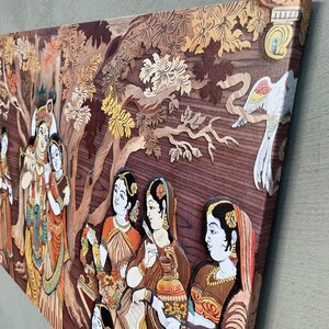 May include: A wood carving depicting a scene from Hindu mythology. The carving features multiple figures, including Krishna and Radha, surrounded by trees and birds. The carving is painted in vibrant colours, including red, yellow, green, and blue.