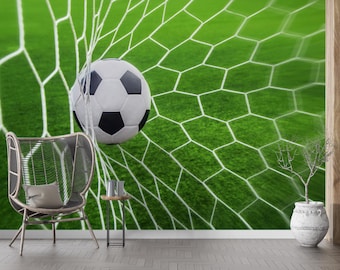 以下が含まれることがあります： 緑色の背景に、ネットに入ったサッカーボール。白と黒のボールはネットの中に部分的にあり、その背後には緑色のフィールドが見えます。椅子、サイドテーブル、装飾的な花瓶が前景にあります。