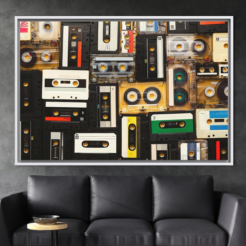 May include: A framed canvas print featuring a collage of vintage cassette tapes. The tapes are arranged in a grid pattern, showcasing various colors and designs. The artwork is set against a dark gray background, with a white frame.