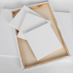 Puede incluir: Tres paneles de lienzo blancos, dos son más pequeños y están apilados uno encima del otro, y uno es más grande y está en un marco de madera. Los paneles están todos en blanco y listos para pintar.