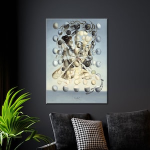 May include: A framed surrealist painting featuring a woman's face composed of floating spheres. The artwork is primarily in shades of beige, gray, and white, with a light blue background. The painting is displayed on a dark gray wall above a black couch.