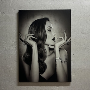 Può includere: Fotografia in bianco e nero di un ritratto di una persona con lunghi capelli scuri, che indossa una camicetta nera e gioielli. La persona sta guardando di lato e ha la bocca leggermente aperta.