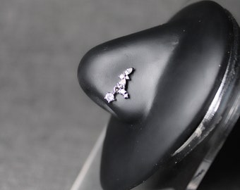 May include: A silver nose ring with a cluster of small clear rhinestones in a curved shape.