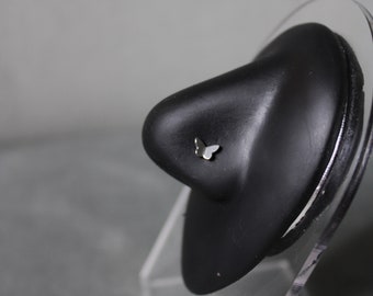 May include: A silver butterfly nose ring on a black display stand.