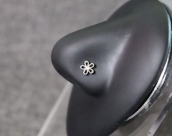 May include: A silver nose ring with a small flower design.