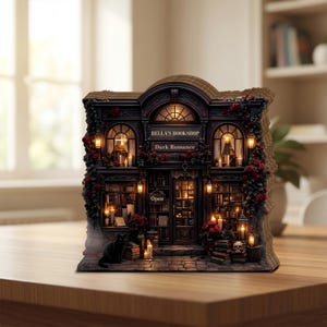 Puede incluir: Una maqueta detallada de Bella's Bookshop, con el texto "Bella's Bookshop Dark Romance" sobre la entrada. La tienda está adornada con rosas rojas, velas y un gato negro. La tienda tiene un letrero de "Open".