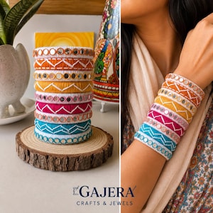 May include: A stack of eight colorful bangles featuring alternating patterns of small circular mirrors and white zigzag embroidery. The bangles are wrapped in thread in shades of orange, yellow, pink, and turquoise, and are displayed on a wood slice.