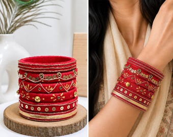 May include: A set of red bangles featuring gold-toned embroidery, metallic sequins, and small studs. The bracelets are stacked together, displaying intricate patterns including zig-zag lines, circular motifs, and smooth metallic bands.