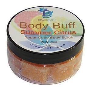 Puede incluir: Un tarro de plástico transparente con tapa negra lleno de cubos de azúcar naranja. La etiqueta dice "Body Buff Summer Citrus Sugar Cube Body Scrub" con ilustraciones de cítricos y la marca "Diva Stuff". El tarro contiene 227 gramos de producto.