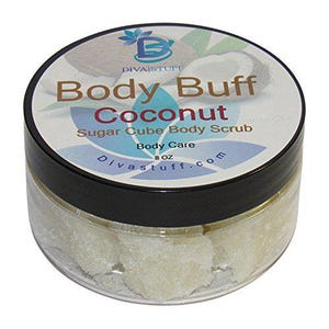 Puede incluir: Un frasco transparente con tapa negra que contiene un exfoliante corporal de azúcar en cubos. La etiqueta dice "Body Buff Coconut Sugar Cube Body Scrub" y "8 oz". El frasco está etiquetado "DivaStuff.com".